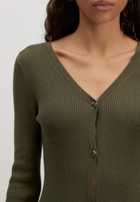 Olivengrüner, gerippter Strickcardigan mit V-Ausschnitt und silberner Knopfverschlus an der Vorderseite. Lange Ärmel runden das Design ab.