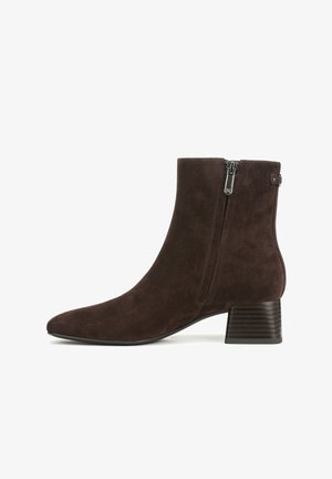 Botte de cheville en daim marron avec un bout pointu, fermeture zippée sur le côté et un talon empilé strié. Texture lisse sans motifs ni accents visibles.