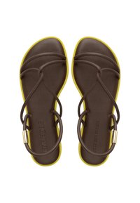 Sandales en caoutchouc marron avec une accentuation jaune sur le bord, présentant plusieurs fines sangles et des accessoires en métal doré. Texture lisse et design minimaliste.