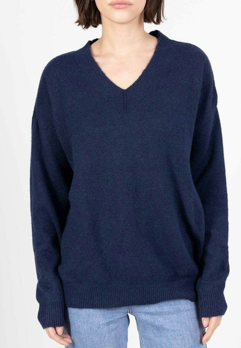Pull oversized bleu marine, avec un col en V, des manches longues et des bords côtelés aux poignets et à l'ourlet. Texture douce, design décontracté.