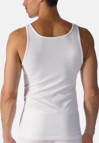 White cotton tank top, sleeveless design, fitted shape, smooth texture, no patterns, clean edges, minimalistic style.