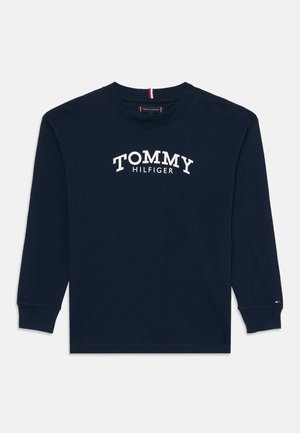 Camisa de manga longa azul-marinho com o texto "TOMMY HILFIGER" em branco na frente e uma pequena bandeira Tommy Hilfiger na extremidade da manga esquerda.