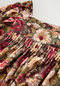 Rochie florală cu un fundal maron, având flori galbene, roz și verzi. Design plisat cu textură adunată la guler.