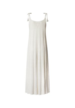 Largo vestido blanco con un patrón texturizado, tirantes ajustables y un parche cuadrado con el logo. La falda acampanada llega hasta el suelo.