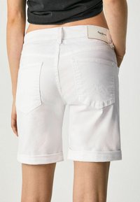 Shorts in denim bianco con orlo arrotolato, tasche posteriori con un motivo montano e un'etichetta in pelle con il marchio sulla vita.