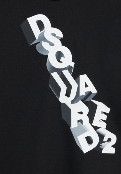 Λευκά γράμματα σε 3D μπλοκ που σχηματίζουν τη λέξη "DSQUARED2" διαγώνια σε μαύρο υφασμάτινο φόντο, με σκιές που δημιουργούν αίσθηση βάθους.