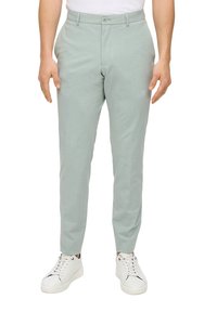Light green chinos with a textured fabric, slim fit, flat front, and single-button closure, worn with white sneakers.