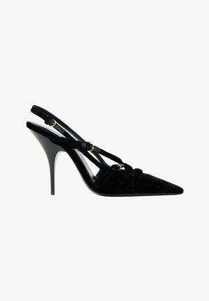 Zapato de salón slingback de terciopelo negro con puntera puntiaguda, tacón alto, tiras finas y detalles de hebilla dorada.