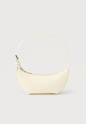 Majhna torbica v obliki polmeseca iz kremnega usnja z enim trakom in zgornjo zadrgo na enobarvnem ozadju.