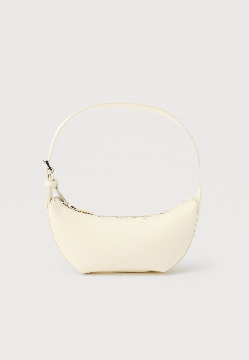 Μικρή τσάντα ώμου σε σχήμα ημισελήνου από κρεμ δέρμα, με ένα λουράκι και επάνω φερμουάρ, σε απλό φόντο.
