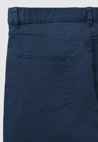 Marineblaue Denim-Jeans mit geradem Schnitt, ausgestattet mit einer Gesäßtasche mit rechteckigem Klappenverschluss und tonalem Nähte. Weiche Textur, ohne sichtbare Muster.