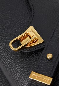 Borsa a tracolla in pelle nera con texture, caratterizzata da una chiusura in metallo dorato e dettagli hardware, cuciture decorative e una targhetta con logo sulla tracolla.