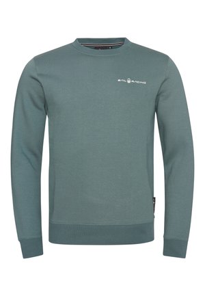 Vihreä, hillityn sävyinen pusero, jossa on pieni valkoinen Sail Racing -logo vasemmassa rinnassa sekä resorireunukset hihansuissa ja helmassa.