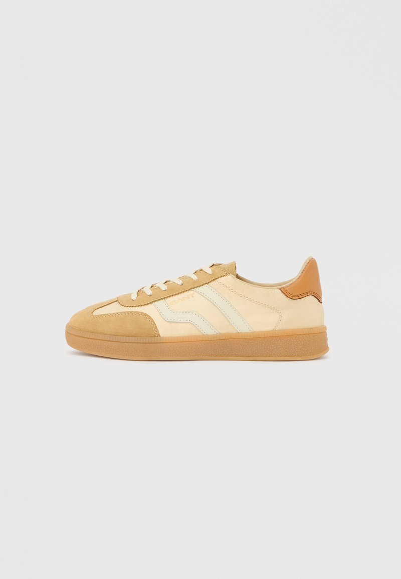 Tan and cream sneakers with suede and leather materials, featuring rubber soles, three stripes, and a brown heel accent.