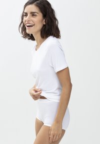 Bílá krátká tričko s kulatým výstřihem, kombinované s bílými vysokými kalhotkami. Hladká tkanina, volný střih a minimalistický design.
