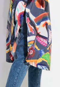 Impermeabile colorato con motivi astratti multicolori. Realizzato in materiale lucido e impermeabile. Presenta una chiusura con bottoni e tasche laterali.