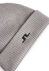 Grå stickad mössa med en texturerad design och en vikbar kant, med en svart zigzag-logotyp som accent på sidan.