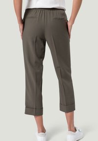 Oliivinvihreät lyhyet housut, joissa on sileä pinta, joustava vyötärö ja käännetyt lahkeet. Sisältää kaksi takataskua. Yhdistetty valkoisiin tennareihin.