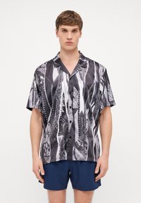 Short-sleeve shirt in black and white with abstract patterns. Lightweight fabric, collar design, and button front detail. Casual style.