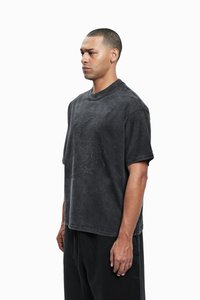 Mørkegrå oversized t-shirt med korte ærmer, der har et struktureret design på brystet, lavet af blødt, falmet bomuldsstof.