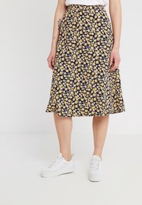 Jupe midi florale avec un fond bleu marine et de petites fleurs jaunes, fabriquée en tissu léger, avec une forme évasée et une taille élastique.