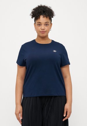 Marineblå bomulds T-shirt med korte ærmer og rund halsudskæring. Har et lille hvidt broderet logo på brystet. Løs pasform.
