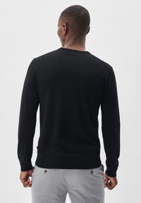 Melnas garas piedurknes džemperis ar apaļo kakla izgriezumu, izgatavots no mīksta auduma. Īpašības ietver pieguļošu dizainu un ribotas piedurknes, kombinēts ar pelēkiem biksēm.