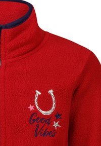 Rote Fleecejacke mit hohem Kragen. Verfügt über ein gesticktes Design eines silbernen Hufeisens und den Text "Good Vibes" mit rosa und blauen Sternelementen.