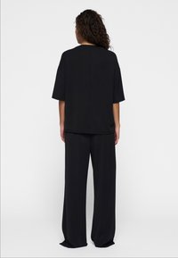 Zwarte losvallende top met korte mouwen en broek met wijde pijpen, gemaakt van zacht fabric, met een eenvoudig ontwerp en minimale detailing.