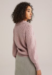 Roze gebreid sweater met geribde manchetten en zoom, voorzien van een textuurpatroon op de achterkant en een klassieke kraag. Zacht en comfortabel materiaal.