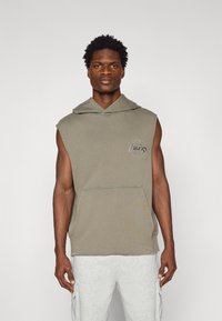 Sweatshirt sem mangas com capuz em algodão verde oliva, com um bolso frontal tipo canguru e uma impressão do logotipo na frente em um design circular.