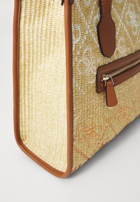 Woven straw handbag with tan leather accents, featuring a quilted pattern and zippered pocket. Side view showcases texture and shape.