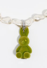 Roheline sametist bunny-amulet säravate roheliste silmadega, kinnitatud ovaalsetest valgest pärlitest kaelaketile, millel on hõbedane klamber.