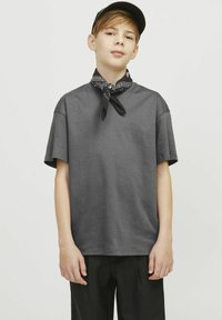 T-shirt grigia in cotone con maniche corte, vestibilità rilassata, abbinata a un bandana nera attorno al collo e pantaloni neri. Design semplice senza motivi.