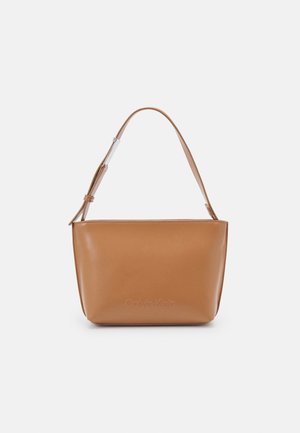 Sac bandoulière en cuir marron avec bandoulière ajustable, bords arrondis et logo discret Calvin Klein embossé à l'avant.