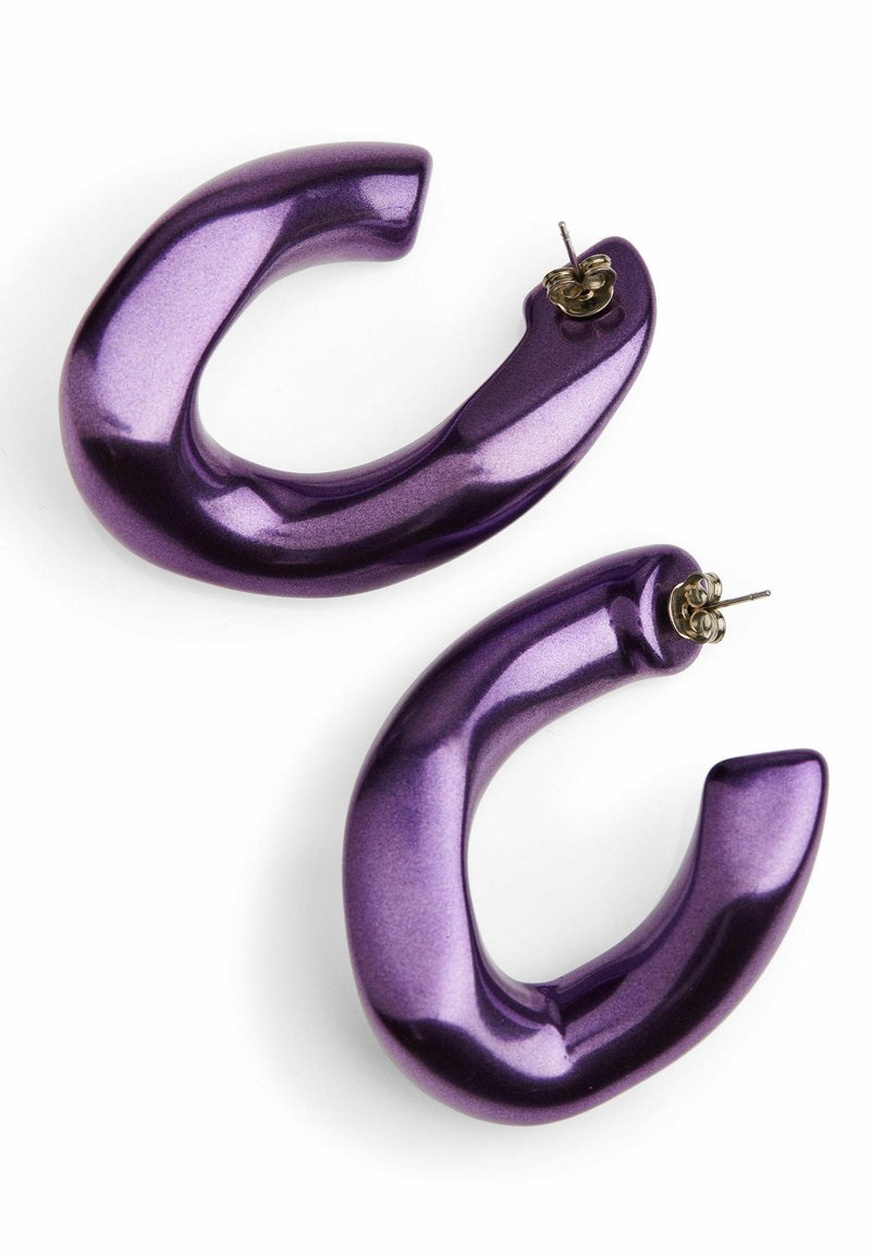 Een paar glanzende, chunky paarse oorringen met stekertjes op een witte achtergrond.