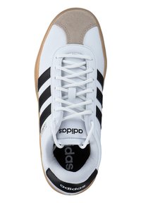 Białe buty sportowe z czarnymi paskami i beżowym zamszowym noskiem. Posiadają płaskie białe sznurowadła oraz gumową podeszwę. Logo na boku i języku.