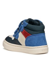 Baskets montantes multicolores avec un design en suède crème, marine, bleu et rouge, dotées d'œillets ronds en métal et d'une semelle blanche texturée.