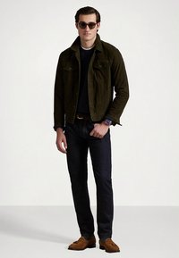 Casaco em camurça verde escura, camisola azul-marinho, jeans escuros e sapatos de vela castanhos. Acessórios incluem óculos de sol castanhos e um relógio. Design simples e ajustado.