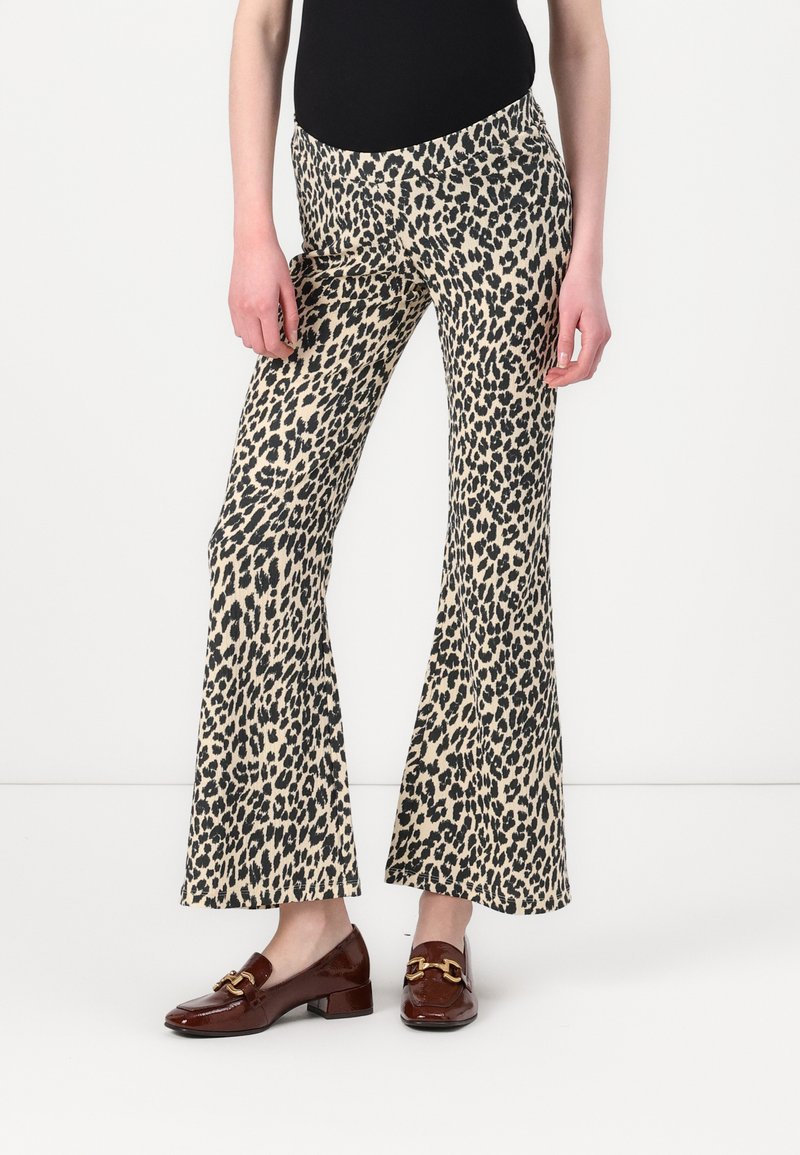 Pantalons évasés en tissu beige et noir à imprimé léopard avec une taille élastique. Associés à des mocassins marron avec des accents en doré.