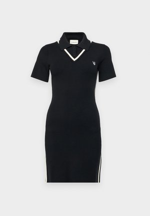 Melnās adītas polo kleitas ar īsām piedurknēm, V veida kakla izgriezumu, kontrastējošu balto apdari un sānu rāvējslēdzējiem. Uz krūtīm ir neliels logo.