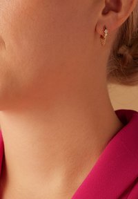 Gold hoop earring with two small clear gemstones and a delicate chain accent. Designed to hang close to the ear lobe.