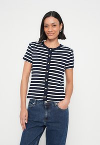 Κοντομάνικο πουκάμισο με ναυτικό μπλε και λευκές ρίγες, στρογγυλή λαιμόκοψη και χρυσή σειρά κουμπιών στο κέντρο. Μαλακό ύφασμα, εφαρμοστή σχεδίαση.