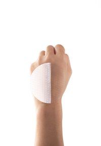 Plaster na dłoni, w kształcie półokręgu, półprzezroczysty z teksturowaną powierzchnią, nałożony na skórę. Białe tło poprawia widoczność.