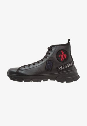 Zapatilla negra de caña alta con suela gruesa, parche bordado de banana roja, parche rectangular azul y parche de texto "AWESOME" en el lateral.