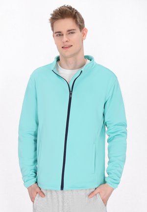 Světle modrá zipová bunda s vysokým límcem, námořnickým zipem a bočními kapsami. Dlouhé rukávy a hladká, pružná látka.