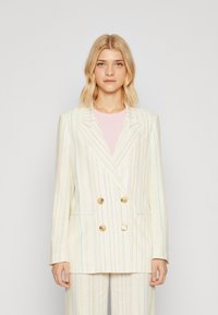 Tweed jasje met dubbele knopen in lichtcrème met pastelstrepen. Gouden knopen, gelapte revers en zijzakken. Getailleerde pasvorm.