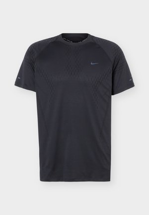 Camiseta deportiva negra de manga corta con patrón sutil y pequeño logo azul de Nike Swoosh en el pecho y las mangas, mostrada sobre fondo liso.