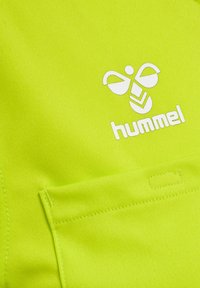 Tessuto sportivo di colore verde neon con logo Hummel bianco e una piccola tasca. Texture morbida con cuciture finemente lavorate.