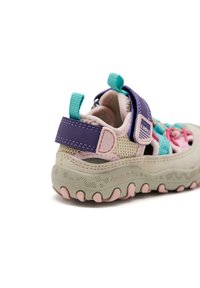 Zapatilla deportiva infantil fabricada con materiales de malla y sintéticos. Con acentos en púrpura claro, rosa y menta. Cierre con correa de velcro y suela texturizada.